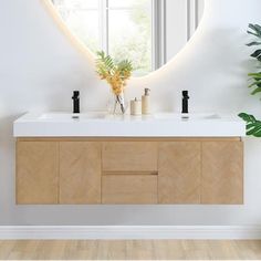 a bathroom with a mirror, sink and plants on the counter top in front of it