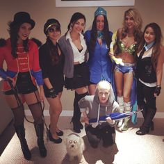 a group of women dressed up in costumes posing for a photo with a white dog