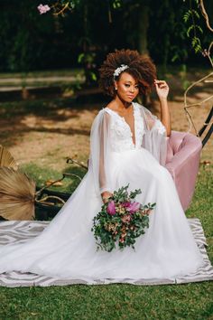 a woman in a white wedding dress sitting on a pink chair holding a flower bouquet