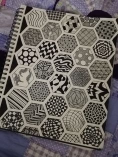 a black and white pattern is on the cover of a notebook, which sits on a quilt