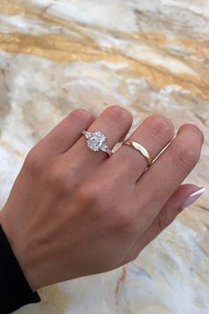 a woman's hand with two gold rings and a diamond ring on her finger