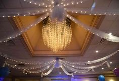 the ceiling is decorated with lights and streamers for an elegant wedding or special event