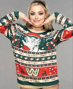 a woman in a christmas sweater posing for the camera with her hands behind her head