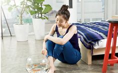 a woman sitting on the floor next to a fish bowl