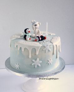 a frosted cake with snowflakes on it and two penguins sitting on top