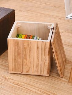 an open wooden box on the floor with books in it and a book case next to it