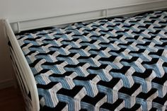 a crocheted blanket sitting on top of a bed next to a white headboard