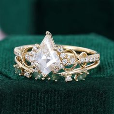 a close up of a ring on a green velvet surface with diamonds in the middle