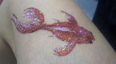 a woman's arm with glitter on it and a fish painted on the side