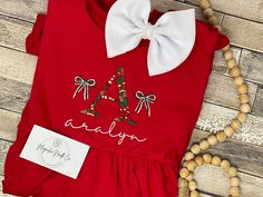 "Christmas dress, embroidered Christmas shirt,Christmas shirt, girls Christmas dress, custom embroidered dress, personalized Christmas outfit custome embroidered Christmas outfit! this can be done on a variety of outfit blanks!  There are various color combos and patterns available! THESE TAKE AROUD A WEEK TO SHIP we are ordering this as needed past one of each size on hand so I want to make sure to set expectations appropriately :) These are USA standard \"snug fitting, flame resistant\" Hey y'all,  First of all, thank you and welcome to our shop! Hi, Thank you so much for your business and support of our passion to create custom items for you! Please know it is our goal to give you the best quality and service we can!  IF YOU NEED THIS SHIPPED OUT in a hurry PLEASE ADD THE RUSHED ORDER F Festive Cotton Holiday Dress For Christmas, Red Embroidered Christmas Dress, Festive Cotton Holiday Dress, Festive Short Sleeve Holiday Dress, Cotton Holiday Dress For Festive Occasions, Festive Holiday Dress With Short Sleeves, Red Embroidered Dress For Christmas, Cotton Holiday Dress, Fitted Cotton Christmas Holiday Dress