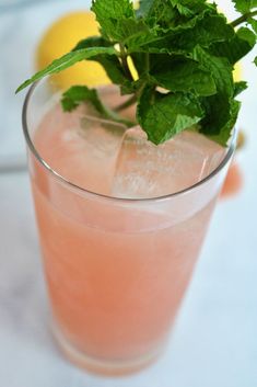 a close up of a drink in a glass on a table with lemons and parsley