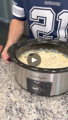 a person holding a bowl of food in front of a crock pot