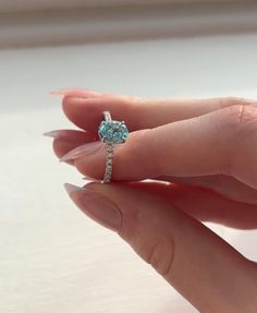 a woman's hand holding an engagement ring with a blue topazte stone