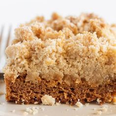 a close up of a piece of cake on a plate with a fork in the background