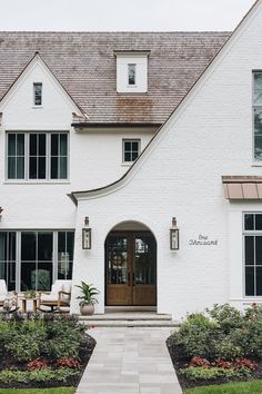 a large white house with two story windows and a front door that leads into the yard