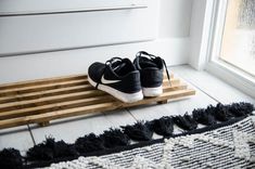 a pair of black shoes sitting on top of a wooden slatted floor next to a window