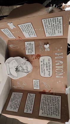 an open cardboard box with paper cutouts and writing on the inside, sitting on top of a table