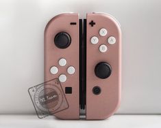 a pink nintendo wii game controller sitting on top of a white table next to a wall