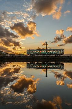 a train traveling over a bridge next to a body of water under a cloudy sky