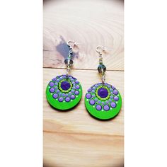 green and purple earrings on wooden table