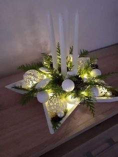 a table topped with candles and ornaments on top of a wooden table covered in greenery