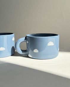 two blue mugs with white clouds on them