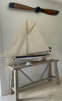 a model sailboat sitting on top of a wooden table in front of a wall