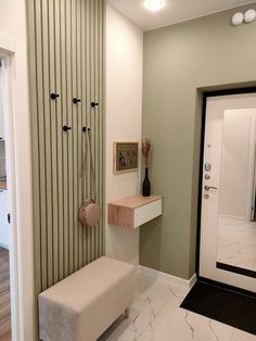 a white bench sitting in the middle of a room next to a wall mounted coat rack