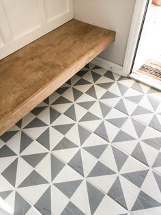 a wooden bench sitting on top of a tiled floor next to a white front door