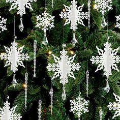 a christmas tree with white snowflakes hanging from it's branches and lights