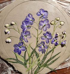 some purple flowers are on a piece of clay