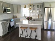 a kitchen with two stools in front of an island and stainless steel refrigerator freezer