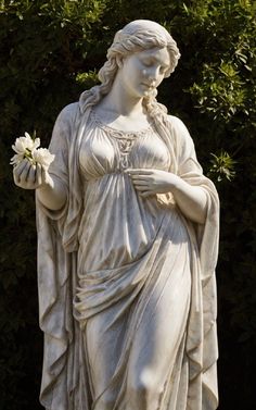 a white statue holding a flower in its hand