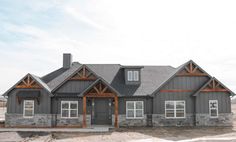 a large gray house sitting on top of a dirt field