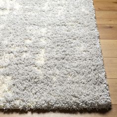 a white area rug on the floor with wood floors and hard wood planks in the background