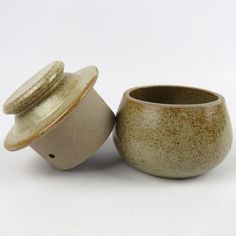 two ceramic cups sitting next to each other on a white surface with one cup in the middle