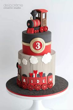 a three tiered cake with a train on it's side and red wheels