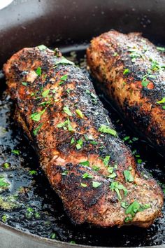 two steaks are cooking in a skillet with some herbs on the top of them