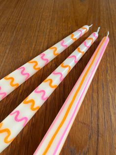 three white and orange straws with designs on them sitting on a wooden table next to each other