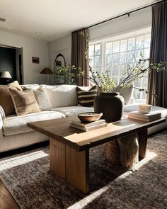 a living room filled with furniture and a wooden table in front of a large window