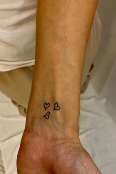 a person with a heart tattoo on their left wrist and the word love is written in small letters