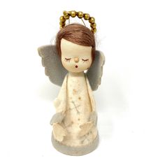 an angel figurine is sitting on a white surface and has her eyes closed