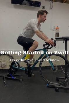 a man riding a bike on top of a metal stand next to a desk with a monitor