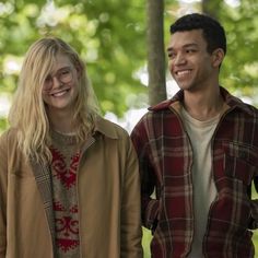 two people standing next to each other in front of some trees and smiling at the camera