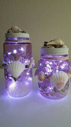 two mason jars with seashells and lights in them