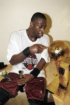 a man sitting on top of a wooden table next to a golden ball and trophy