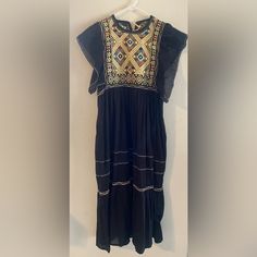 This Is Such A Beautiful And Unique Dress, Very Well Made. I Can Tell It Was Made With Love So This Will Fit Someone Who Wears A Small Or A Medium. If Your Bra Size Is Bigger Than A 36b This Will Probably Not Fit You. To Be Honest, It Looks Brand New. No Tags To Indicate Size But I Just Tried It On (See Video) And I'm A Medium Feels Like Linen To Me And There's That Beautiful Bodice Embroidery. The Back Closes With A Tassels. I'm 5'3" And It Falls To My Ankles Black Folk Embroidered Summer Dress, Black Short Sleeve Dress For Festivals, Black Dress With Gold Embroidery For Festive Occasion, Festive Black Dress With Gold Embroidery, Black Bohemian Embroidered Dress With Geometric Pattern, Black Embroidered Bohemian Dress, Black Folk Dress With Floral Embroidery, Casual Embroidered Dress For Festive Occasions, Black Folk Dress With Embroidered Hem