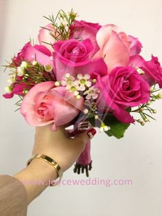 a hand holding a bouquet of pink roses