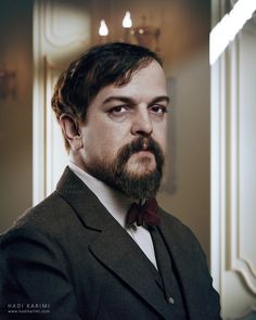 a man with a beard wearing a suit and bow tie in front of a mirror