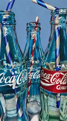 three glass coke bottles with straws in them